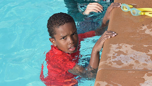 boy holding onto side of pool