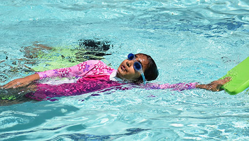 young girl swimming with kickboard